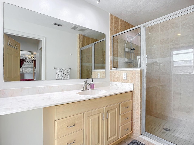 bathroom featuring vanity, a textured ceiling, walk in shower, and tile patterned floors