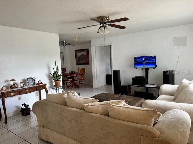 living room with a textured ceiling, light tile patterned floors, and ceiling fan