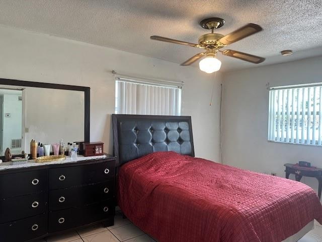 tiled bedroom with a textured ceiling and ceiling fan