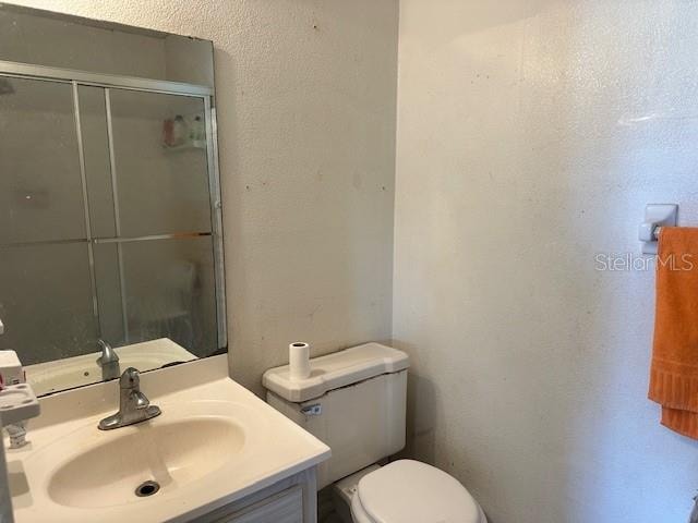 bathroom with vanity, toilet, and a shower with shower door