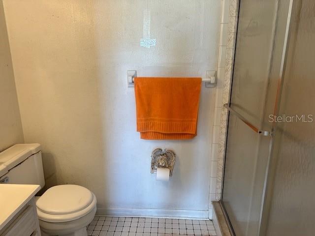 bathroom with vanity, tile patterned flooring, toilet, and an enclosed shower