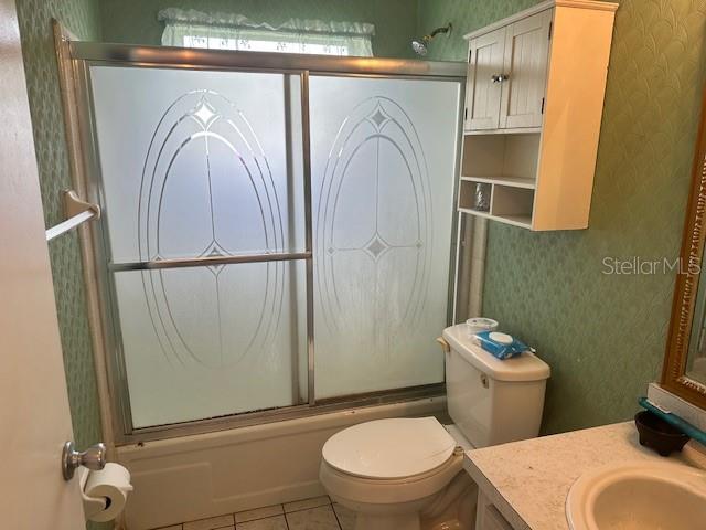 full bathroom featuring toilet, combined bath / shower with glass door, vanity, and tile patterned floors