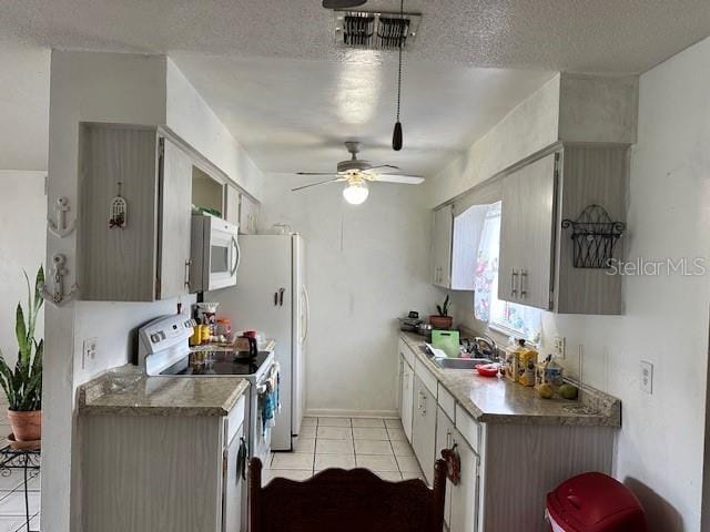 kitchen featuring sink, electric stove, a textured ceiling, ceiling fan, and light tile patterned floors