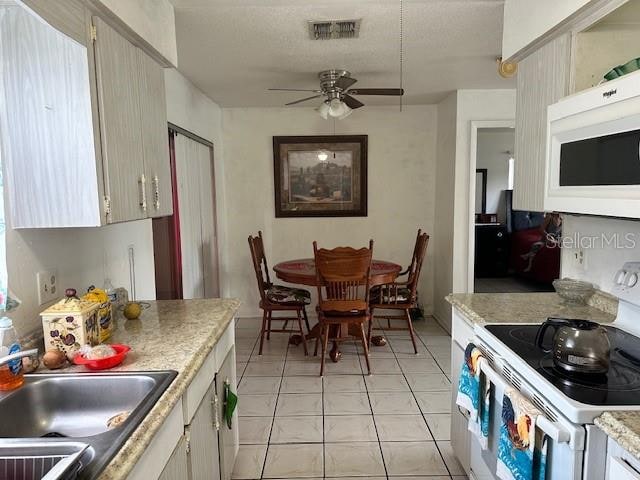 kitchen featuring ceiling fan, sink, light tile patterned floors, and white appliances