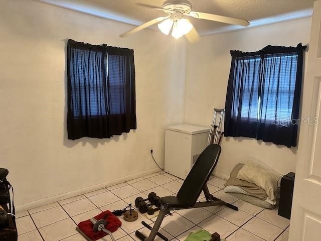 exercise area featuring light tile patterned floors and ceiling fan