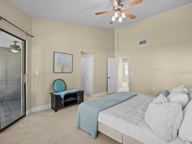 carpeted bedroom featuring ceiling fan, ensuite bath, a textured ceiling, and a closet