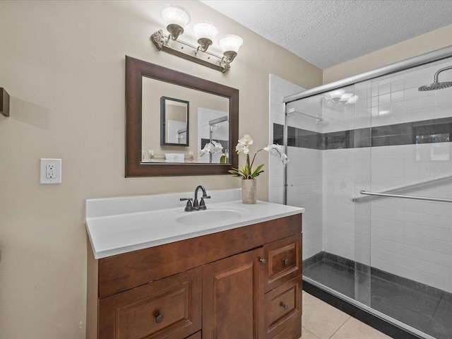 bathroom featuring tile patterned flooring, a textured ceiling, vanity, and a shower with door