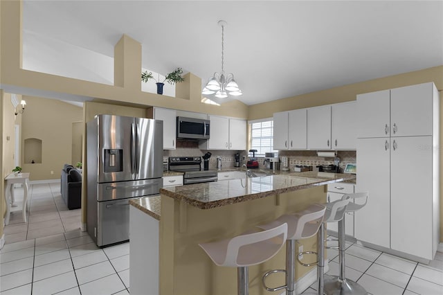 kitchen with light tile patterned flooring, white cabinetry, appliances with stainless steel finishes, decorative backsplash, and a center island