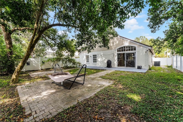 back of property with central AC unit, a patio, and a yard