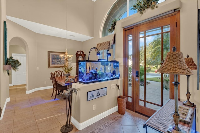 tiled entryway with a high ceiling and an inviting chandelier