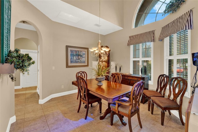 tiled dining area featuring a high ceiling and an inviting chandelier