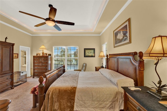 carpeted bedroom with a tray ceiling, ceiling fan, and ornamental molding