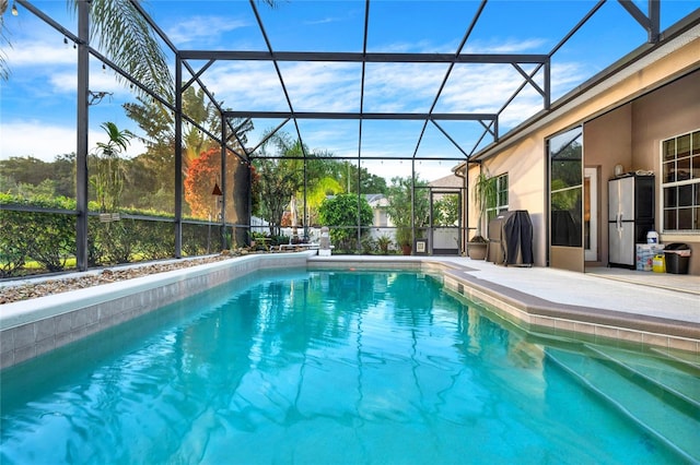 view of swimming pool featuring glass enclosure and a patio