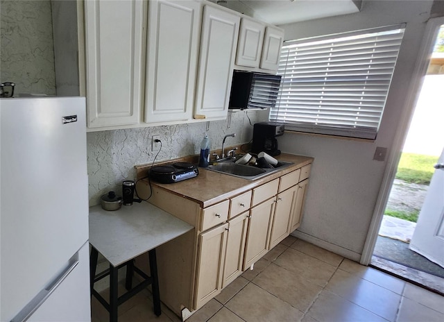 kitchen with light tile patterned flooring, white fridge, and sink