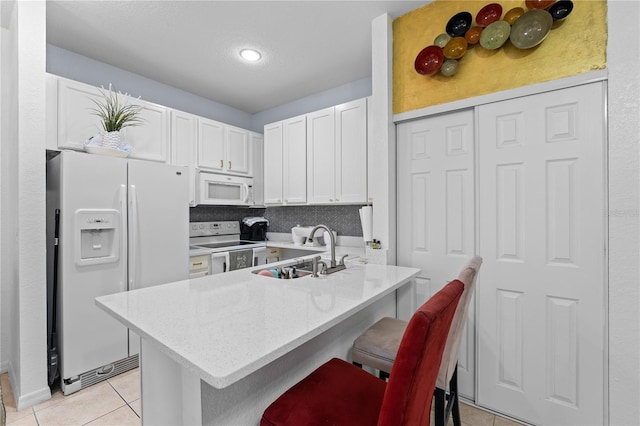 kitchen featuring white cabinets, a breakfast bar, white appliances, light tile patterned floors, and sink