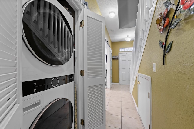 washroom featuring a textured ceiling, stacked washer and dryer, and light tile patterned floors