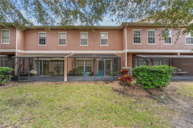 rear view of property featuring a sunroom and a lawn