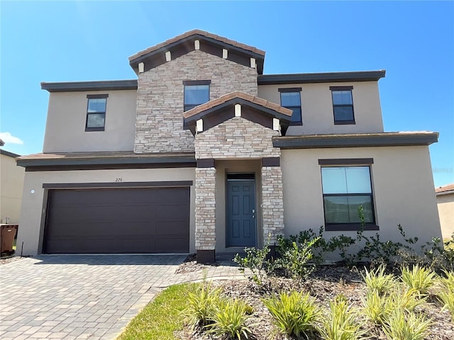 226 Macaulays Cv, Haines City, FL 33844 - view of front of property featuring stone siding, stucco siding, an attached garage, and decorative driveway