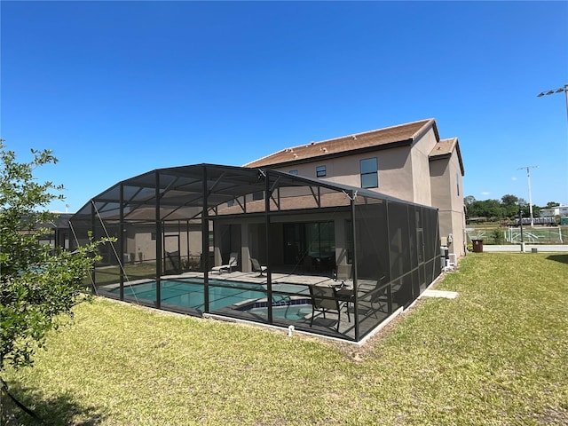 rear view of property featuring glass enclosure, a yard, and a patio area