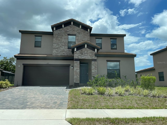 226 Macaulays Cv, Haines City, FL 33844 - view of front of home featuring stone siding, stucco siding, a garage, and decorative driveway