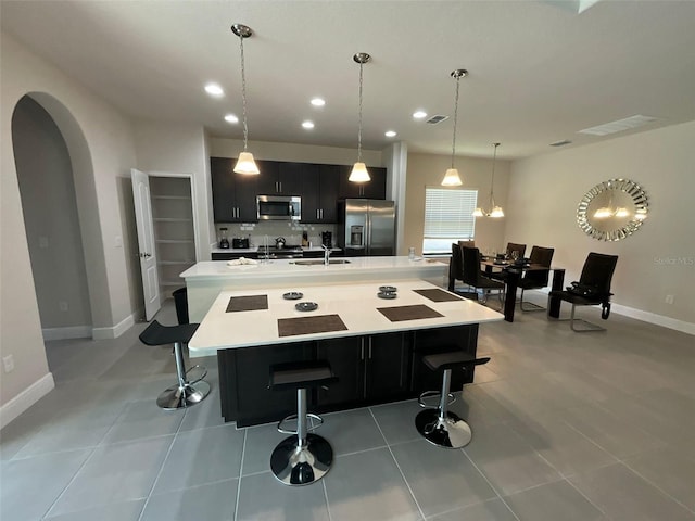 kitchen featuring pendant lighting, sink, stainless steel appliances, a spacious island, and a kitchen bar