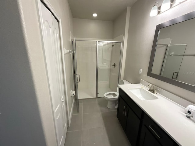 bathroom featuring tile patterned flooring, a shower with door, vanity, and toilet