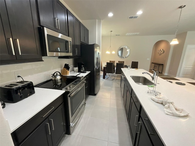 226 Macaulays Cv, Haines City, FL 33844 - kitchen featuring appliances with stainless steel finishes, dark cabinets, light countertops, hanging light fixtures, and arched walkways