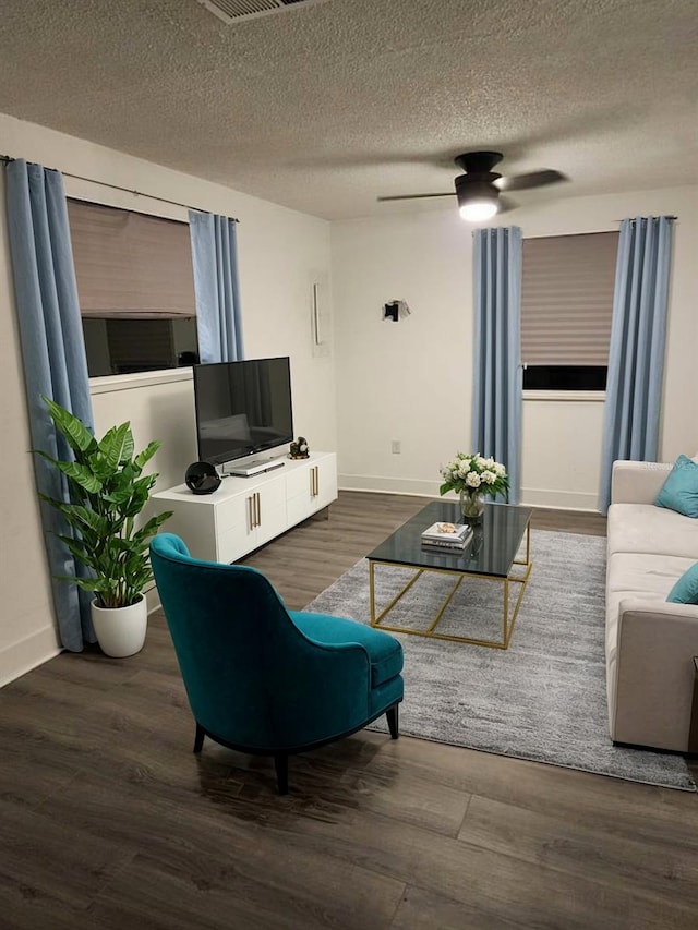 living room featuring ceiling fan, dark hardwood / wood-style flooring, and a textured ceiling