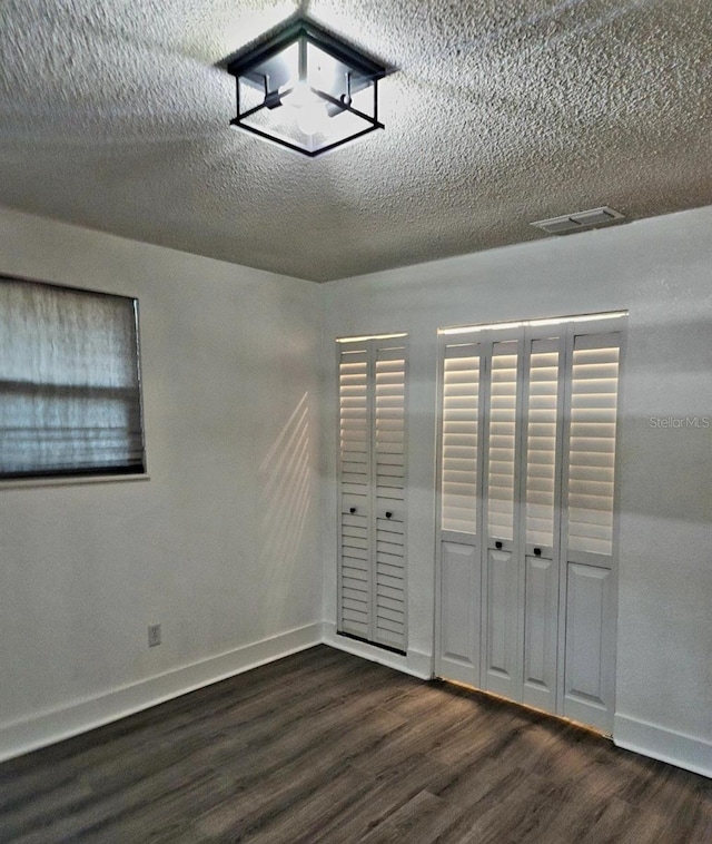 unfurnished bedroom with a textured ceiling, dark hardwood / wood-style floors, and a closet