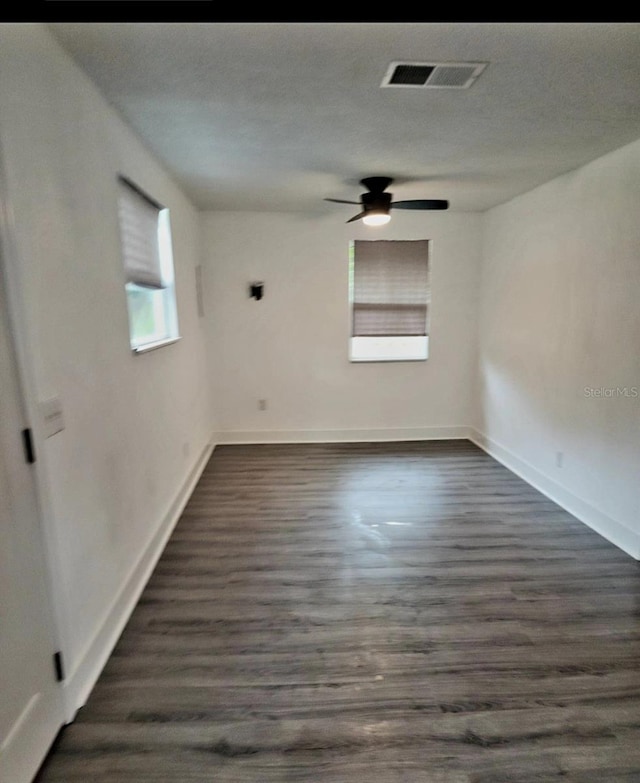 spare room with a textured ceiling, ceiling fan, and dark wood-type flooring