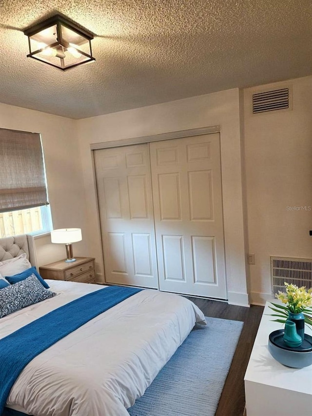 bedroom featuring a closet, dark hardwood / wood-style floors, and a textured ceiling