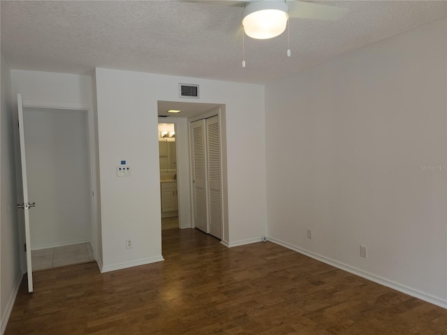 unfurnished bedroom featuring a closet, ceiling fan, a textured ceiling, and dark hardwood / wood-style flooring