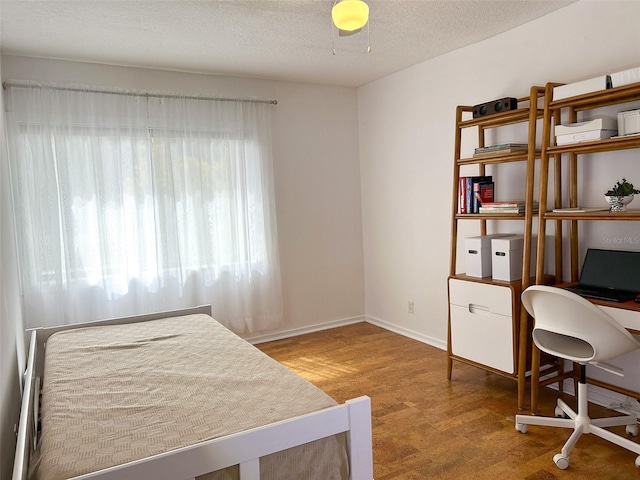 bedroom featuring a textured ceiling, ceiling fan, and hardwood / wood-style flooring