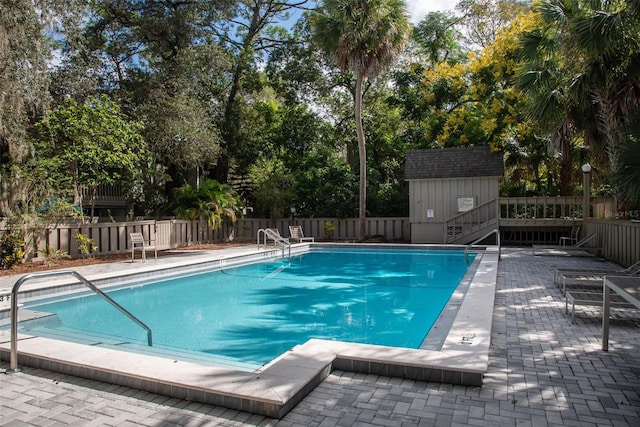 view of pool featuring a patio and a shed