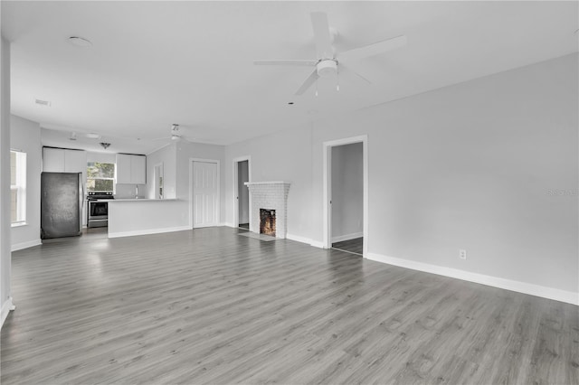 unfurnished living room with light hardwood / wood-style floors, a fireplace, and ceiling fan