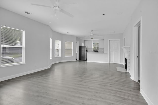 unfurnished living room with ceiling fan, light hardwood / wood-style flooring, and a fireplace