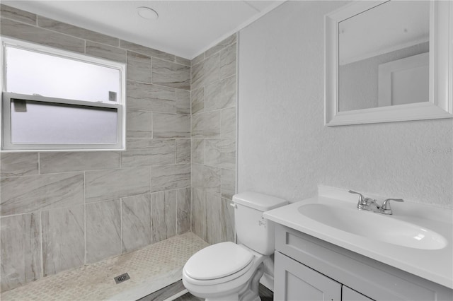 bathroom with toilet, vanity, and a tile shower