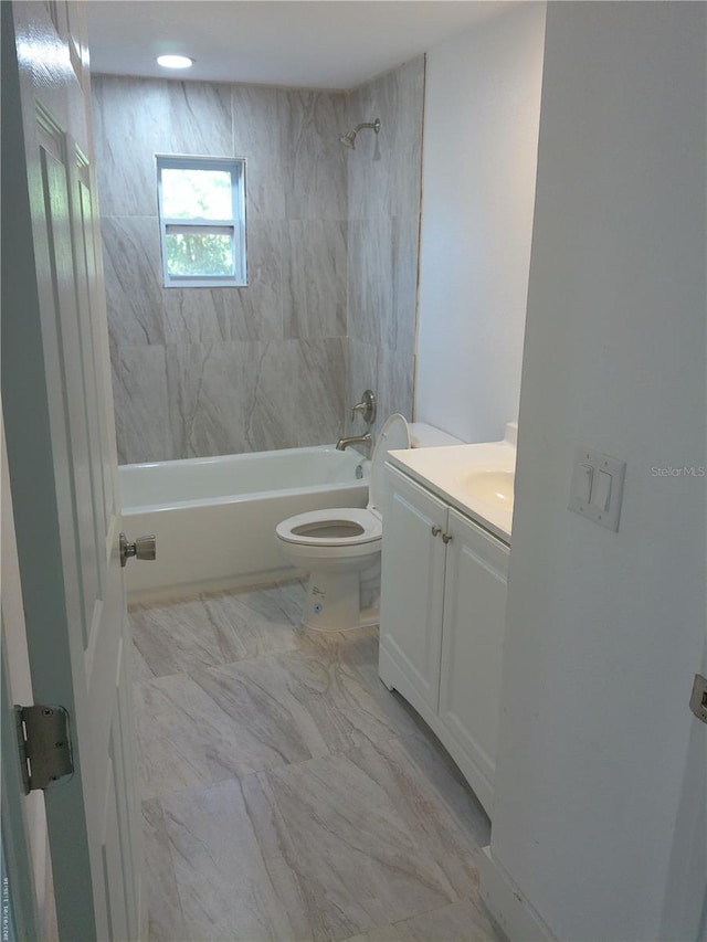 full bathroom featuring tiled shower / bath, vanity, and toilet