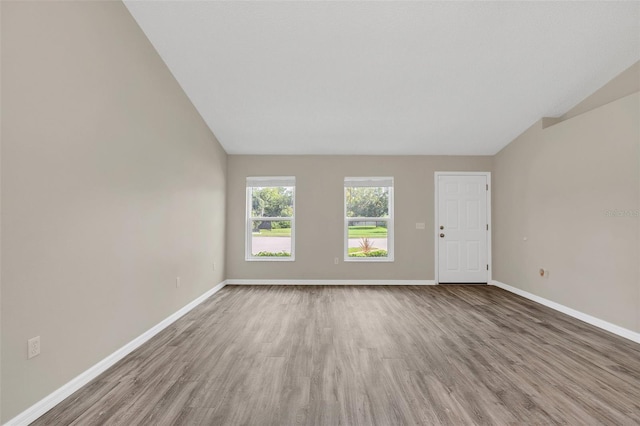 unfurnished room featuring wood-type flooring and vaulted ceiling