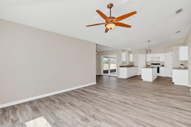 unfurnished living room with a textured ceiling, ceiling fan, light hardwood / wood-style flooring, and vaulted ceiling