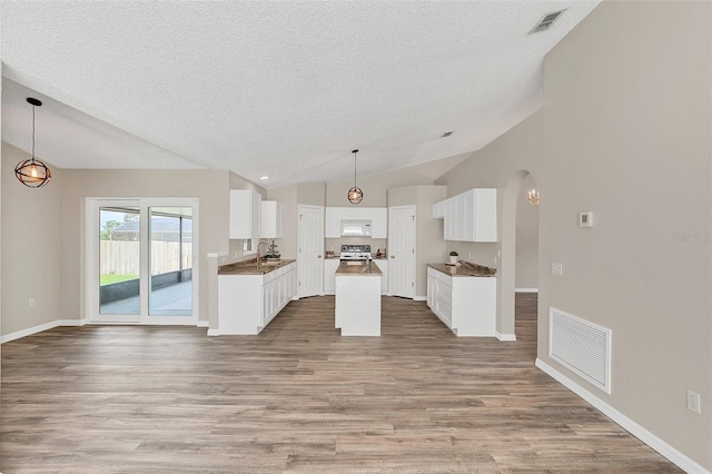 kitchen with white cabinets, light hardwood / wood-style floors, hanging light fixtures, and lofted ceiling