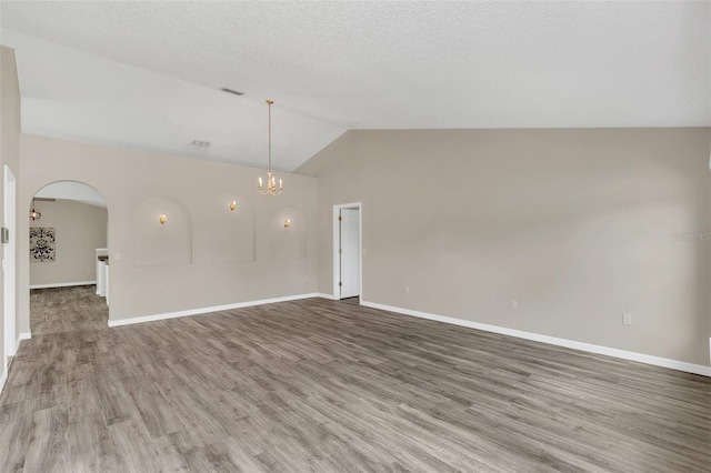 spare room featuring hardwood / wood-style floors, vaulted ceiling, and a notable chandelier