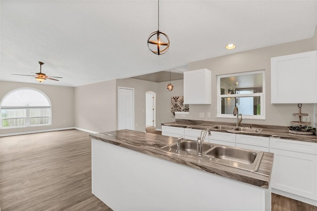 kitchen featuring white cabinets, pendant lighting, wood-type flooring, and sink