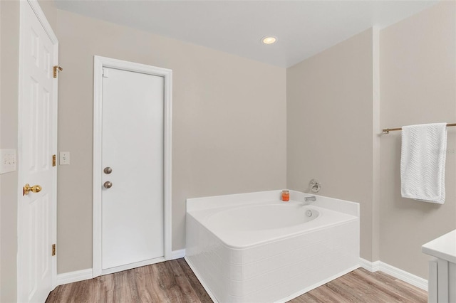 bathroom featuring hardwood / wood-style floors, a washtub, and vanity