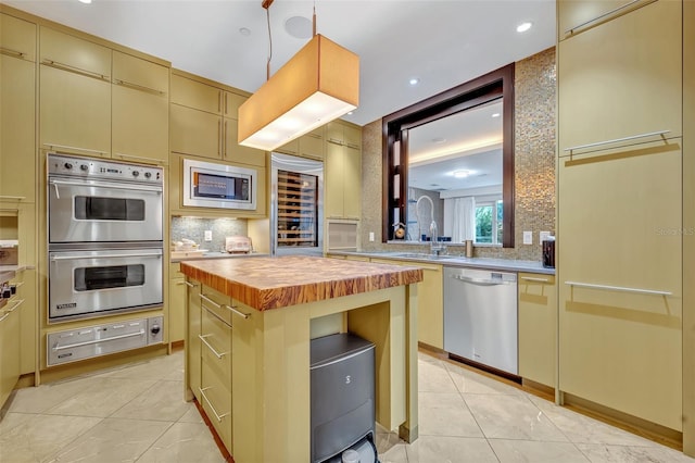 kitchen featuring beverage cooler, a kitchen island, appliances with stainless steel finishes, wooden counters, and sink