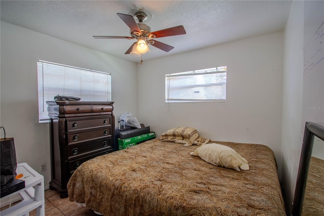 bedroom with a textured ceiling, light tile patterned floors, and ceiling fan