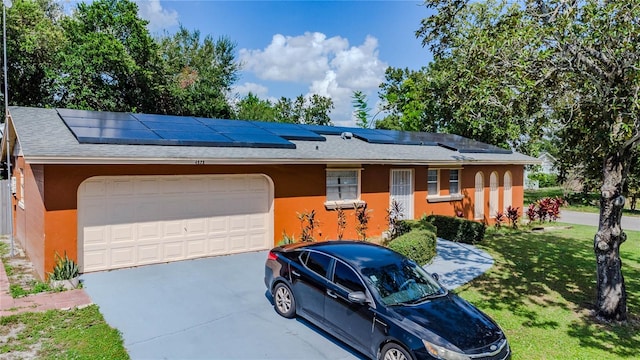 ranch-style house with a front yard, a garage, and solar panels