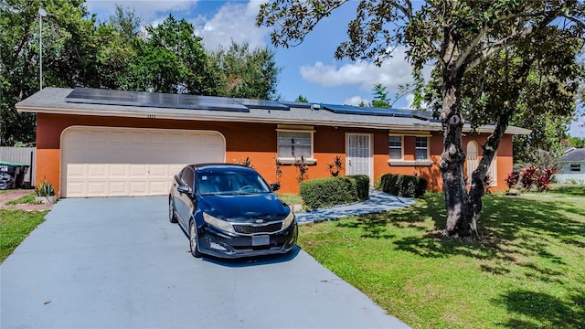 single story home featuring a garage, solar panels, and a front lawn