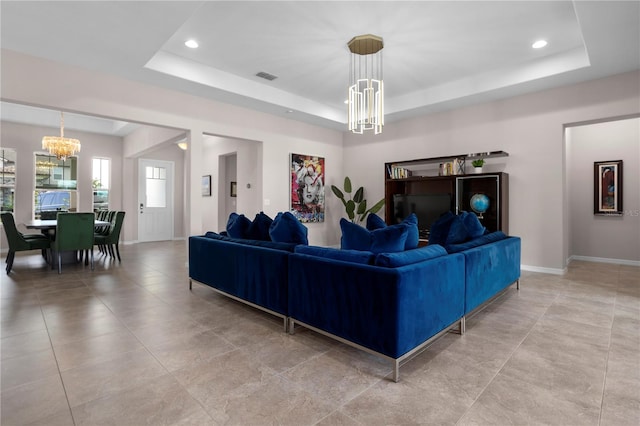 living room with a notable chandelier and a tray ceiling