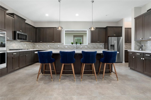 kitchen with appliances with stainless steel finishes, dark brown cabinetry, a center island, and pendant lighting